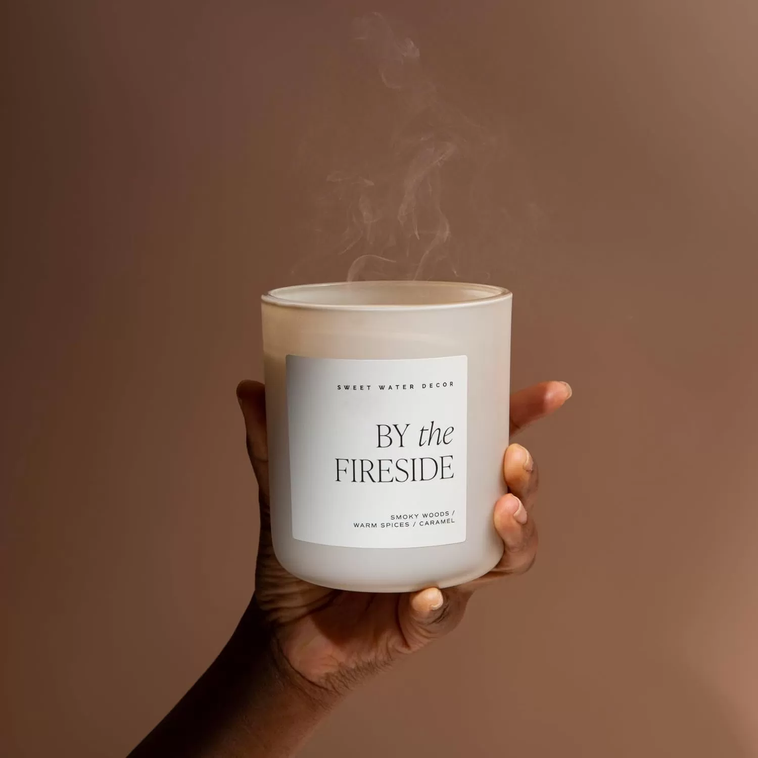 imageSweet Water Decor By The Fireside Candle  Vanilla Caramel Amber Tonka Smoky Woods Musk Winter Scented Soy Candles for Home  15oz Tan Jar 70 Hour Burn Time Made in the USATan